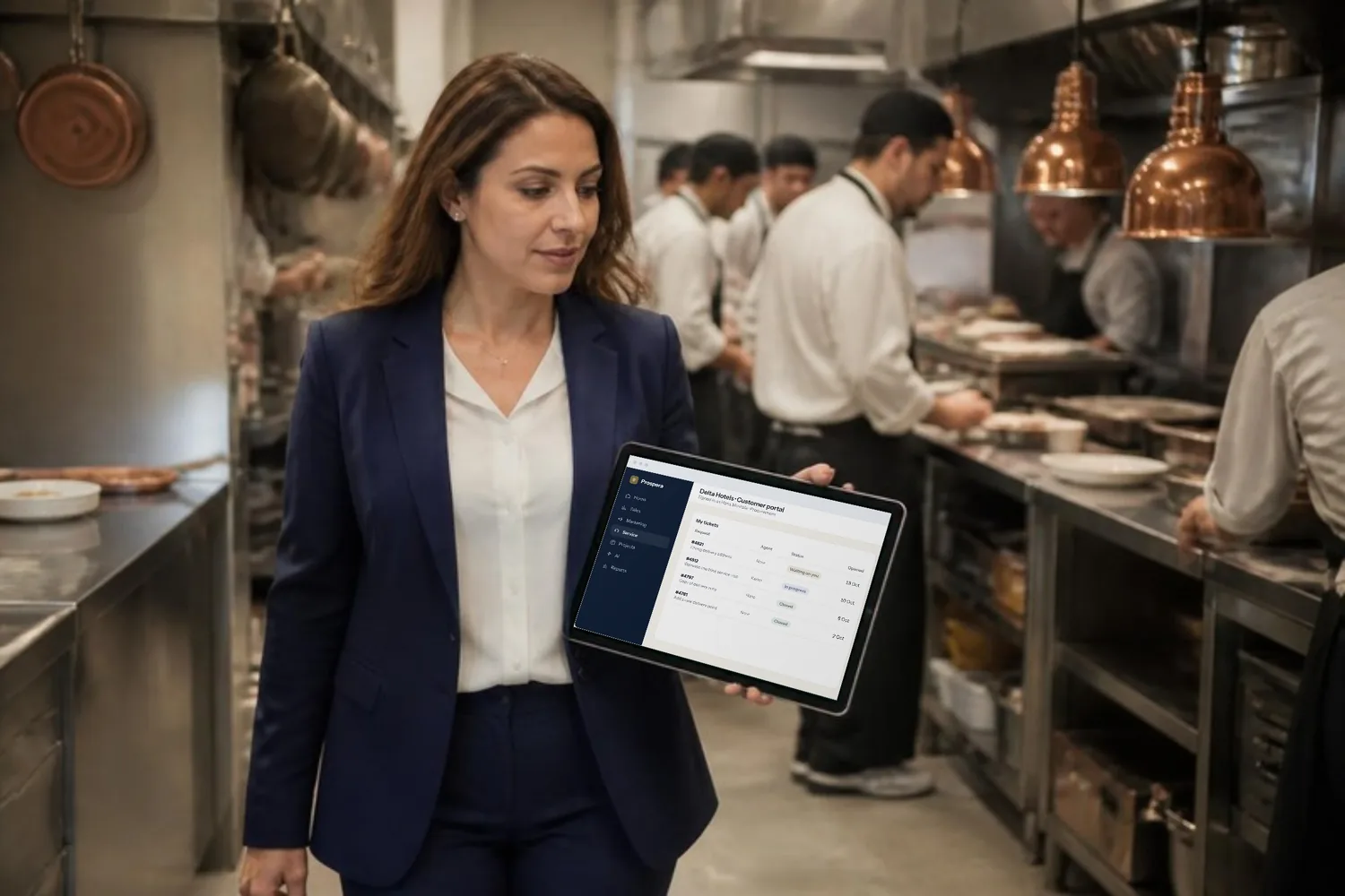 A hotel procurement manager checks a service request in the customer portal on her tablet while walking through the hotel kitchen