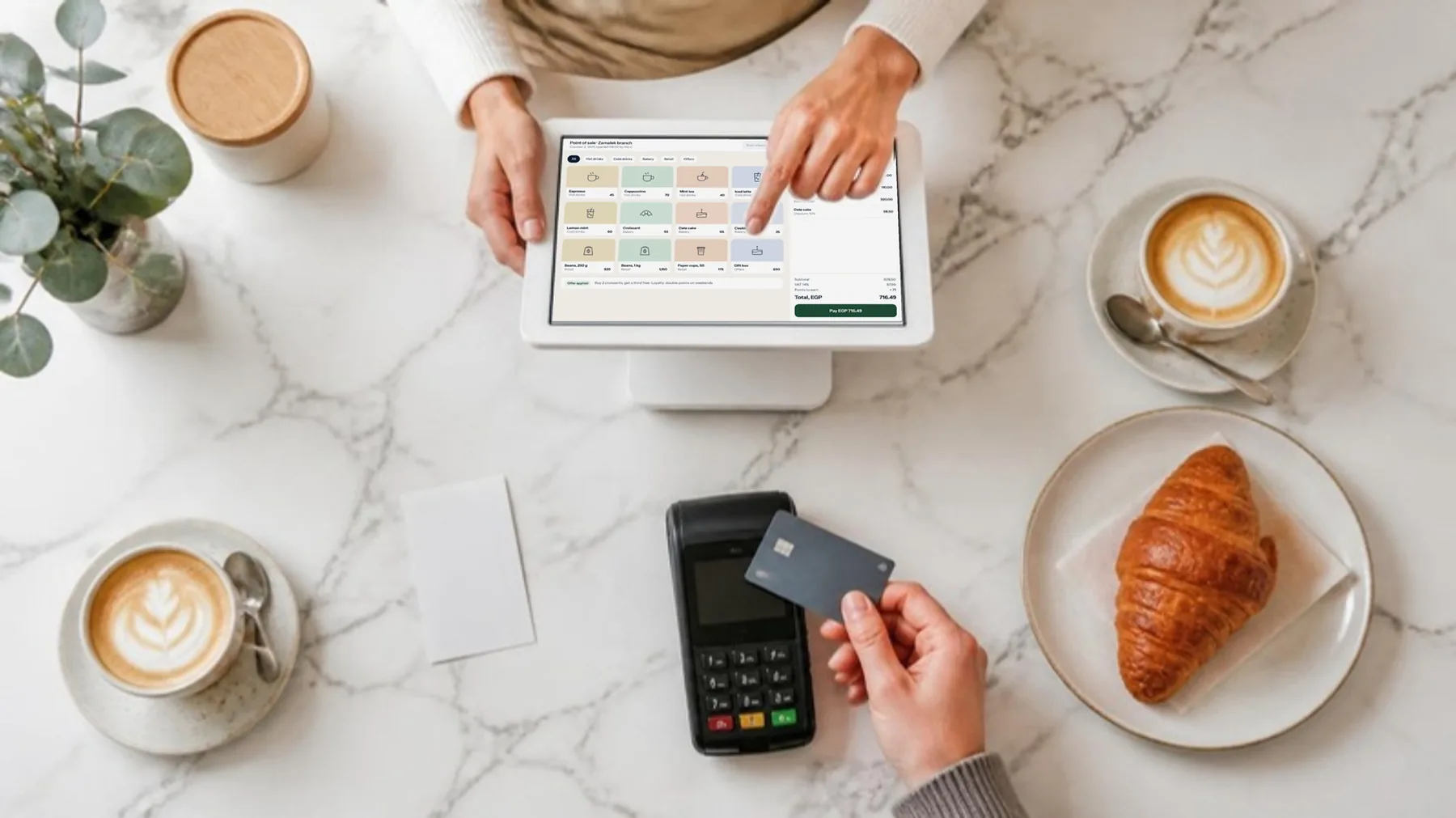 A customer paying by card at a cafe counter while the cashier rings up the order on Prospera Books